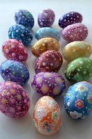 Colorful Easter eggs decorated with dots, flowers and swirls in vibrant spring colors arranged on white background. Festive holiday celebration craft photography.