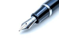 Close-up macro shot of luxury fountain pen nib in black and silver on white background, showing intricate metalwork detail and professional writing instrument design.