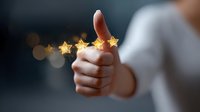 Thumbs up gesture with magical glowing five star rating floating above, customer satisfaction and positive feedback concept on dark background with bokeh effect.