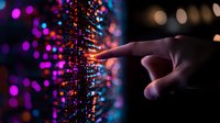 Human finger touching glowing digital particles with purple and blue bokeh lights in dark background, representing technology interface and virtual reality interaction.
