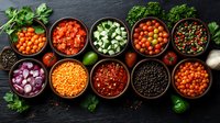 Fresh colorful ingredients in rustic bowls on dark slate background featuring lentils, cherry tomatoes, diced cucumber, red onions, and mixed peppercorns.