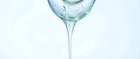 Cocktail glass with clear liquid and ice cubes on white background, isolated for beverage, bar, and hospitality design use.