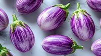Fresh striped purple eggplants with green stems arranged on light gray background, organic healthy vegetables pattern for cooking and food design.