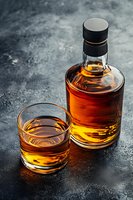 Glass of aged amber spirit and bottle on dark concrete background with dramatic lighting and reflections. Suitable for beverage marketing.