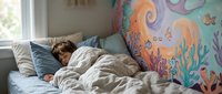 Young woman sleeping peacefully in cozy bed with colorful underwater mural wall art featuring sea creatures and coral reef design in bright bedroom interior.