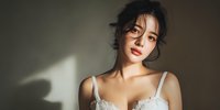 Young Asian woman in white lace lingerie with soft natural lighting and shadows creating intimate boudoir photography mood for fashion and beauty content.