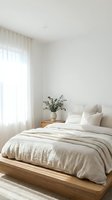 Serene minimalist bedroom with wooden bed frame, neutral linen bedding, eucalyptus plant in ceramic vase, sheer curtains, and soft natural light for home decor and interior design projects.