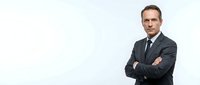 Confident middle-aged Caucasian businessman in dark suit with crossed arms against white background for corporate presentations and marketing materials.