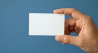 Hand holding blank white business card on blue background for corporate branding and professional identity design mockup template.