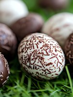 Chocolate Easter eggs decorated with sprinkles on fresh green grass background. Close-up macro shot shows white and dark chocolate confectionery details.