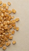 Golden amber crystals scattered on neutral beige background. Raw mineral specimens for geology, wellness, and natural product photography.