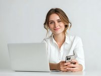 Young Caucasian woman in white shirt smiling while working with laptop and smartphone against light background. Professional remote work concept.