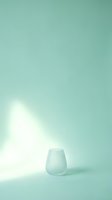 Frosted glass cup on mint green background with soft natural light and shadow, suitable for product display, minimalist design, and modern home decor projects.