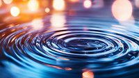 Water ripples create concentric circles with colorful bokeh lights reflecting on liquid surface in abstract motion pattern for relaxation and meditation concepts.
