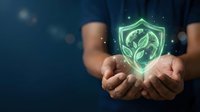 Hands holding glowing green shield with leaf symbol representing eco-friendly protection, sustainability, and environmental security for business and technology concepts.