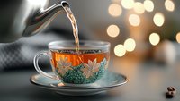 Steaming hot tea being poured into vintage floral teacup with bokeh lights in background, cozy autumn morning atmosphere with warm drink and decorative porcelain.