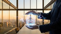 Businessman hands protecting digital security lock icon with city skyline background through office windows at sunset for cybersecurity concept.