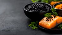 Fresh raw salmon fillet with black caviar, herbs and spices on dark stone background. Luxury seafood composition with copy space for restaurant menu.
