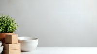Minimalist kitchen counter with white ceramic bowls, wooden blocks and fresh green plant creating clean modern home interior design space.