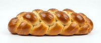 Fresh braided challah bread with golden crust and sesame seeds on white background, traditional Jewish bakery product isolated for culinary designs.