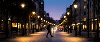 Evening pedestrian street with warm glowing lanterns and illuminated storefronts during twilight hour creating romantic urban atmosphere for shopping and leisure.