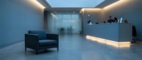 Modern minimalist office lobby with reception desk and leather chair in blue ambient lighting for corporate interior design.