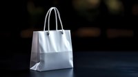 White paper shopping bag with handles standing on dark surface against blurred background for retail and commercial use.