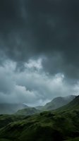 Dramatic stormy sky with dark clouds looming over lush green rolling mountains and valleys, capturing moody weather conditions for atmospheric landscape projects.