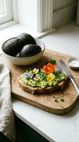 Avocado toast topped with edible flowers on wooden board, fresh avocados in ceramic bowl, bright kitchen setting with natural light.