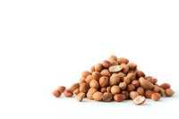 Mixed nuts pile including hazelnuts, macadamia and peanuts on white isolated background, raw organic healthy snack for vegetarian protein diet and nutrition.