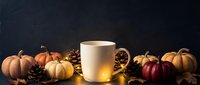 Warm mug of cider or tea surrounded by autumn pumpkins, pinecones, and fall foliage on dark background for seasonal beverage marketing and holiday designs.