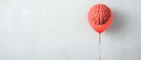 Pink balloon shaped as human brain with string against light gray background, minimalist creative concept for psychology and mental health awareness.