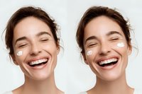 Young woman with radiant smile and facial cream dots on cheeks against white background, showcasing skincare routine and natural beauty.