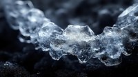 Clear ice formation with crystalline structure on dark rocky surface creating natural winter abstract composition for seasonal design projects.