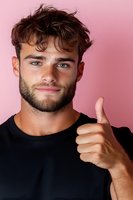 Young man with beard showing thumbs up gesture against pink background, wearing black t-shirt. Positive facial expression and confident smile.