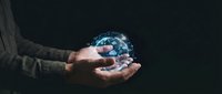 Hands holding glowing digital globe with blue network connections against dark background, representing global connectivity, technology, and worldwide business communication.