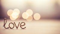 Coffee beans spelling love word with warm bokeh lights background creating romantic atmosphere for Valentine's Day cards and wedding invitations.
