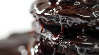 Dark chocolate layers with glossy melted coating and dripping syrup creating rich, decadent texture for food photography and dessert marketing.