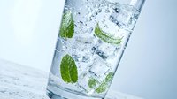 Refreshing sparkling water with fresh mint leaves and ice cubes in clear glass. Cool beverage for summer hydration and healthy lifestyle concepts.