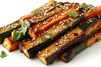 Grilled zucchini sticks glazed with sweet soy sauce, garnished with sesame seeds and fresh cilantro leaves on white background, appetizing vegetarian dish.
