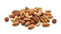 Mixed nuts assortment with almonds, walnuts, cashews, pecans and hazelnuts isolated on white background for healthy snacking and cooking recipes.