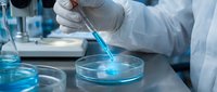 Scientist in white gloves using pipette to transfer blue liquid sample in laboratory petri dish for medical research and chemical analysis experiments.