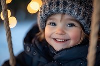 Smiling child wearing winter knit hat and warm jacket outdoors with blurred bokeh lights in background, capturing pure joy and seasonal magic.