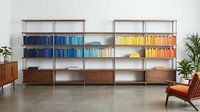 Modern mid-century walnut bookshelf unit with colorful books organized by spectrum, featuring clean lines and minimalist design for contemporary interior.