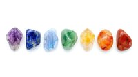 Isolated gemstones in rainbow colors including amethyst, lapis lazuli, aquamarine, emerald, citrine, carnelian and ruby on white background for design use.