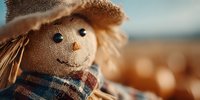 Cheerful scarecrow with burlap face and straw hat in autumn field during golden hour sunset. Harvest season decoration for fall festivals and seasonal displays.