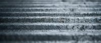 Close-up view of weathered concrete steps with textured surface showing wear patterns and aging details in monochrome tones for architectural backgrounds.