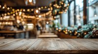 Empty wooden table with blurred festive cafe interior background, warm bokeh lights creating cozy holiday atmosphere.