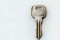 Single metal door key on white background with copy space, minimalist composition showing security and access concept for business and real estate.