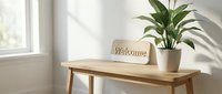 Wooden welcome sign on a light oak bench beside a green potted plant in a bright, minimalist entryway with soft natural light.